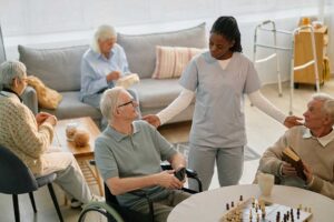 Older adult and family member arranging labeled clothing and photographs in a bright assisted living room.