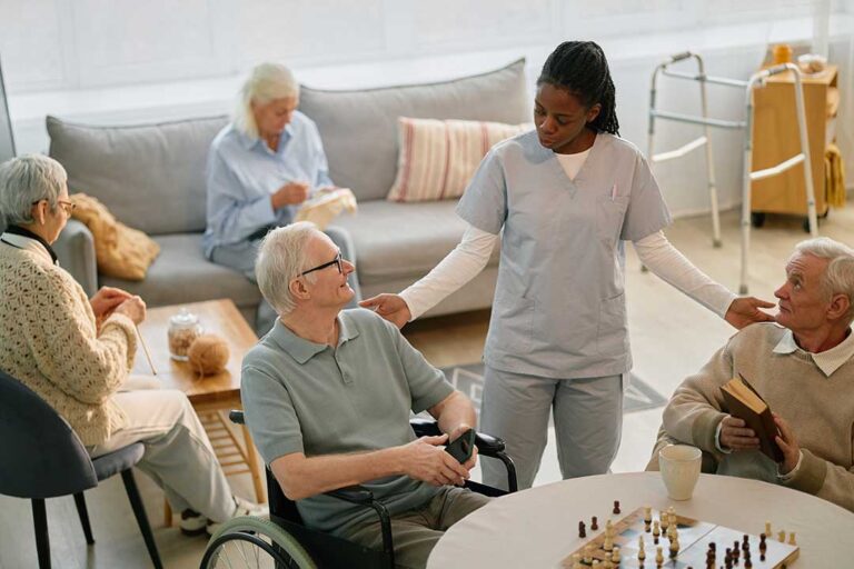 Older adult and family member arranging labeled clothing and photographs in a bright assisted living room.